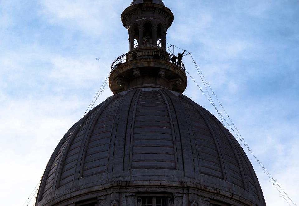 Workers hoist up the the Christmas lights from a lower level to the top of the dome on the observation deck of the Illinois State Capitol in 2017.