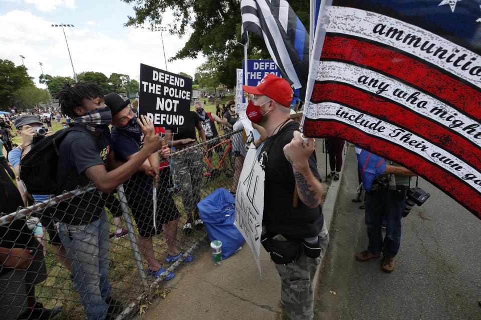 A man wearing a mask and hat in support of President Donald Trump, right, exchanges words with people attending a Juneteenth rally, left, Friday, June 19, 2020, in Boston. Juneteenth commemorates when the last enslaved African Americans learned in 1865 they were free, more than two years following the Emancipation Proclamation. (AP Photo/Michael Dwyer)
