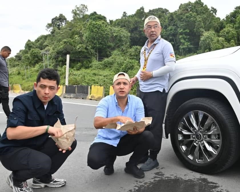 Al-Sultan Abdullah leaning against a vehicle with the Crown Prince of Pahang Tengku Hassanal Ibrahim Alam Shah (left) and Tengku Amir Nasser Ibrahim Shah eating packed rice with their hands during the Kembara Kenali Borneo in September 2023.