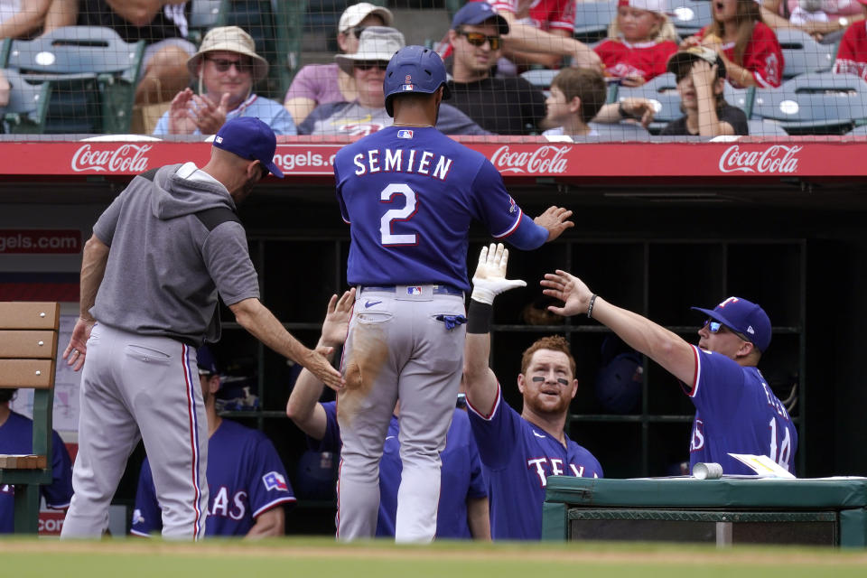 Texas Rangers' Marcus Semien is congratulated by teammates in the dugout after scoring on a single by Nathaniel Lowe during the first inning of a baseball game against the Los Angeles Angels Sunday, July 31, 2022, in Anaheim, Calif. (AP Photo/Mark J. Terrill)