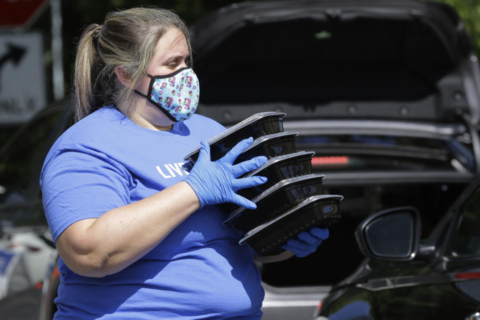 Kristina Ellis prepares to load prepared meals into a vehicle as United Way of Broward County partners with the Miami Dolphins football team to distribute backpacks and meals to military families in need during the coronavirus pandemic, Wednesday, Aug. 5, 2020, in Fort Lauderdale, Fla. (AP Photo/Lynne Sladky)