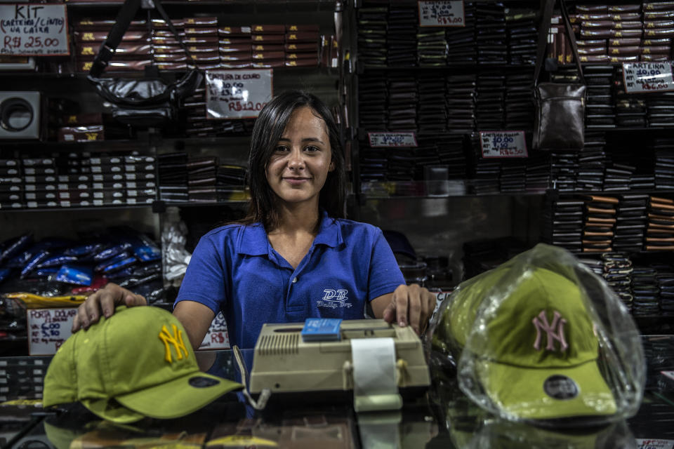 Matheus Gustavo, a la izquierda, aprendiz en una tienda de Río, hablaba con un gerente sobre las diversas gorras disponibles de los Yankees. (Dado Galdieri/The New York Times)