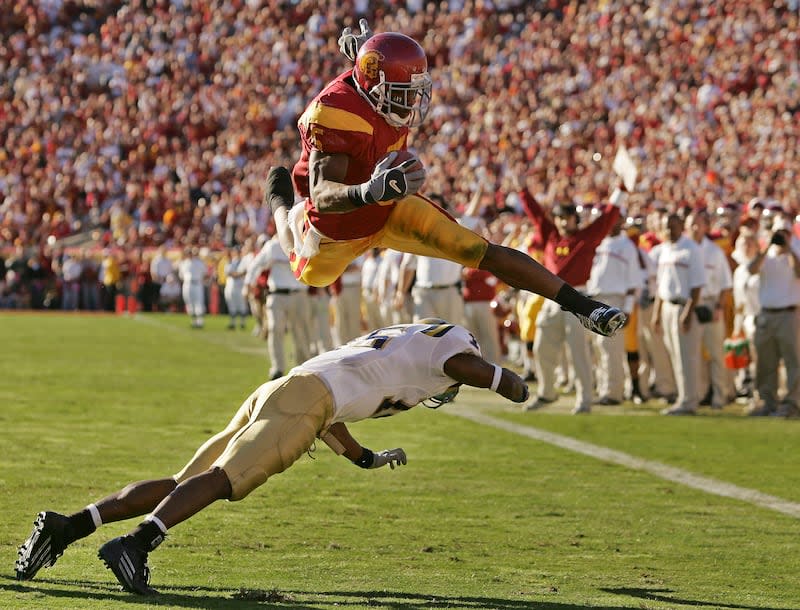 Southern California's Reggie Bush leaps over <a class="link " href="https://sports.yahoo.com/ncaaf/teams/ucla/" data-i13n="sec:content-canvas;subsec:anchor_text;elm:context_link" data-ylk="slk:UCLA;sec:content-canvas;subsec:anchor_text;elm:context_link;itc:0">UCLA</a> defender Marcus Cassel as he rushes 13 yards for a touchdown at the Los Angeles Memorial Coliseum, Saturday, Dec. 3, 2005. | Chris Carlson, Associated Press