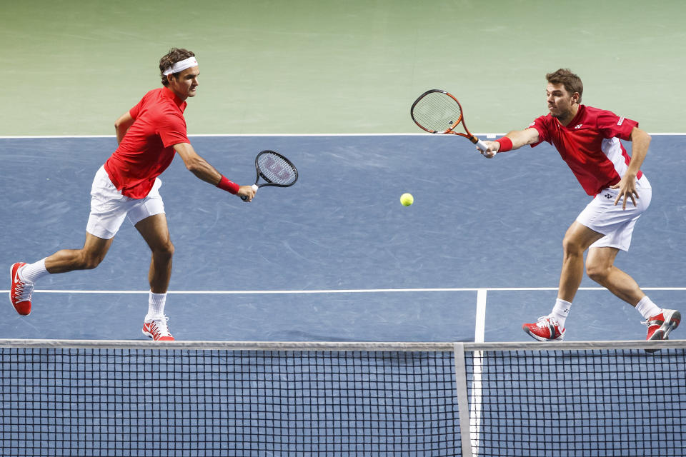 Los jugadores de Suiza, Stanislas Wawrinka, derecha, y Roger Federer, devuelven una pelota contra los kazajos Aleksandr Nedovyesov y Andrey Golubev en los cuartos de final de la Copa Davis el sábado, 5 de abril de 2014, en Ginebra. (AP Phtoo/Keystone,Salvatore Di Nolfi)