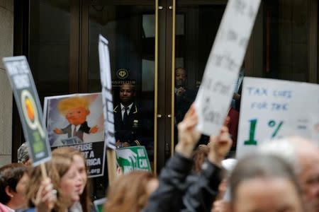 Employees of a private club watch as demonstrators march past Trump Tower while protesting through Manhattan demanding U.S. President Donald Trump release his tax returns, in New York, U.S., April 15, 2017. REUTERS/Lucas Jackson