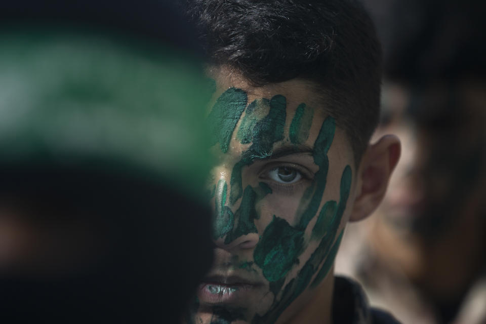 A Palestinian youth with a green face painting, attends a rally marking the 34th anniversary of Hamas movement\s founding, in Gaza City, Friday, Dec. 10, 2021. Gaza’s Hamas rulers collect millions of dollars a month in taxes and customs at a crossing on the Egyptian border – providing a valuable source of income that helps it sustain a government and powerful armed wing. After surviving four wars and a nearly 15-year blockade, Hamas has become more resilient and Israel has been forced to accept that its sworn enemy is here to stay. (AP Photo/ Khalil Hamra)