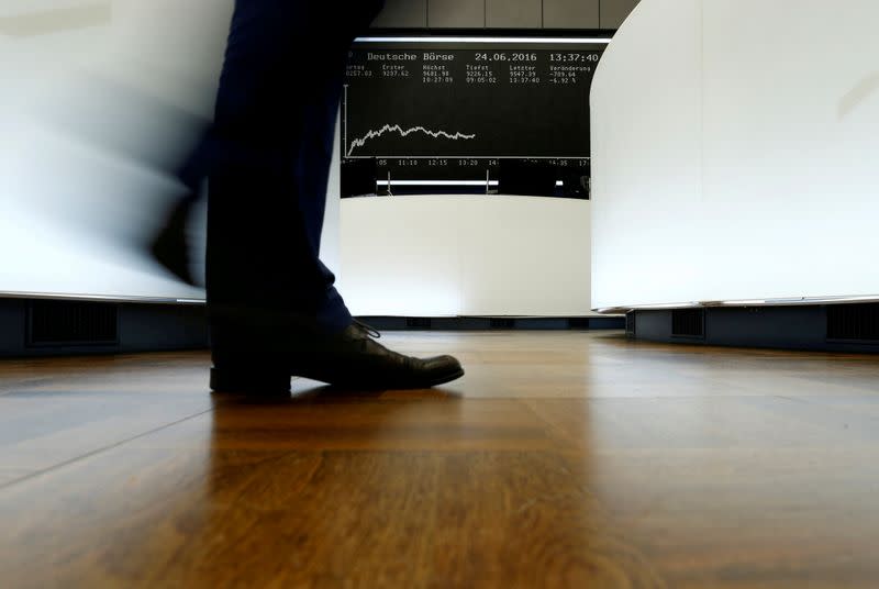 FILE PHOTO: A trader walks past the German DAX Index board on the trading floor at the Frankfurt stock exchange