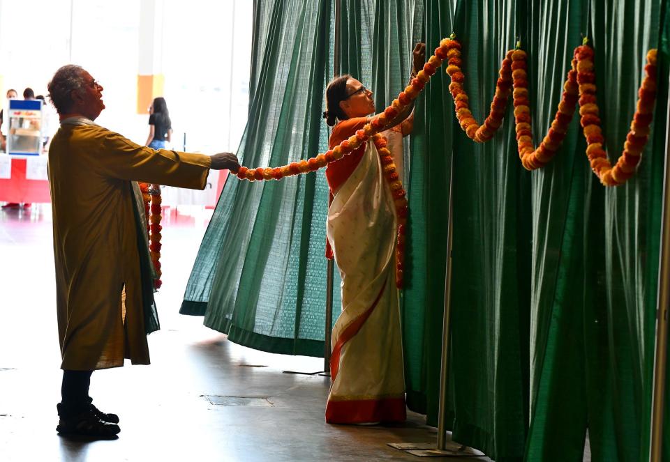 Carolyn and Sahdev Passey of Holden string garland near an entrance during the India Society of Worcester's India Day festival at the DCU Center Saturday.
