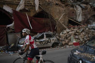 A cyclist rides past destroyed buildings and cars in a neighborhood near the site of last week's explosion that hit the seaport of Beirut, Lebanon, Tuesday, Aug. 11, 2020. (AP Photo/Felipe Dana)