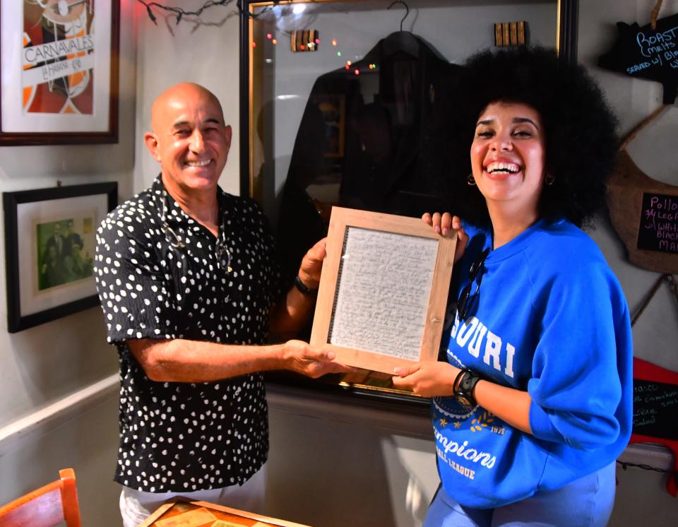 Chila Lynn and Alfredo Hernandez, owner of El Ambia Cubano, hold her July 2017 message in a bottle. Now framed, the letter is displayed in the restaurant dining room.