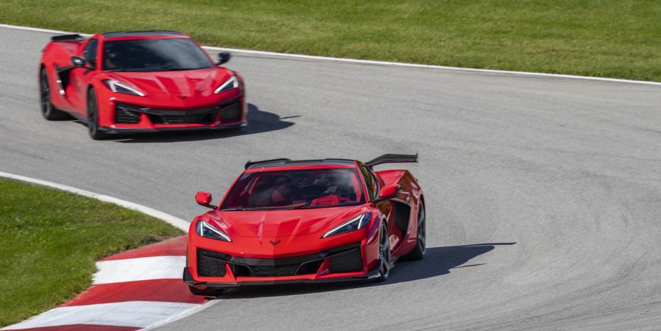 view of two 2023 chevrolet corvette z06s in torch red driving on a track