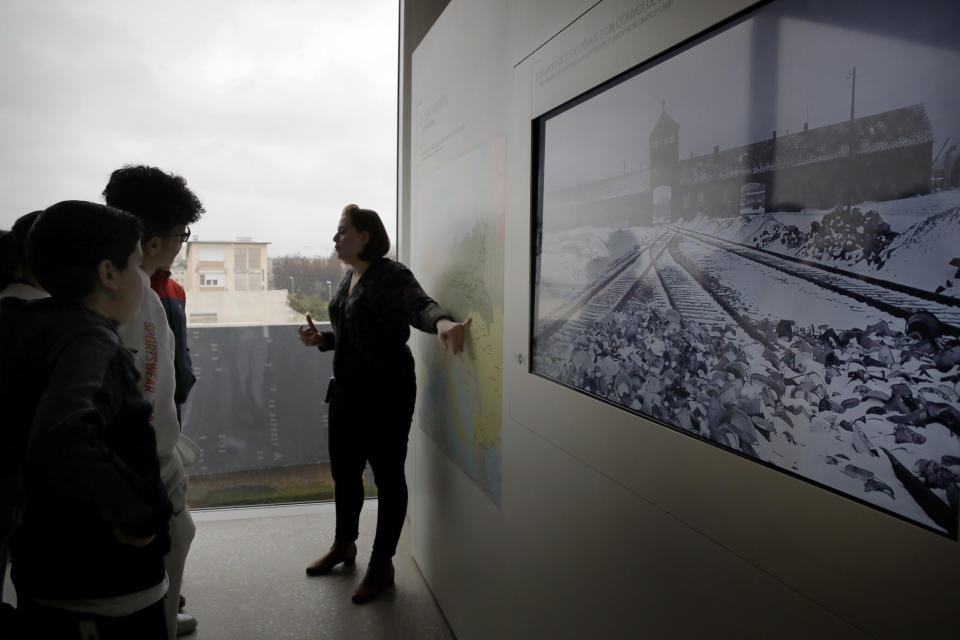 In this photo taken on Thursday Jan. 30, 2020, students listen to guide Alix Quere during a workshop dedicated to the Holocaust remembrance at the Drancy Shoah memorial, outside Paris. A French Holocaust survivor Victor Perahia was 9 when his family was seized by the Nazis, and couldn't bear to speak about what happened for 40-years, but is now telling his story to schoolchildren at Drancy, backdropped by the buildings that once imprisoned him. (AP Photo/Christophe Ena)