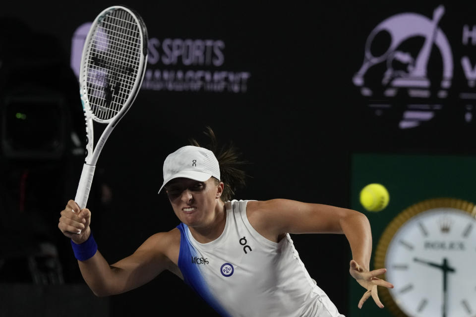 Iga Swiatek, of Poland, returns a shot to Ons Jabeur, of Tunisia, during a women's singles match at the WTA Finals tennis championships, in Cancun , Mexico, Friday, Nov. 3, 2023. (AP Photo/Fernando Llano)