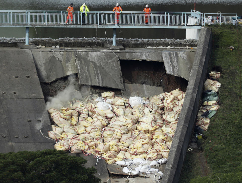 A bag of aggregate, a mixture of sand, gravel and stone, is thrown onto the damaged Toddbrook Reservoir near the village of Whaley Bridge,in Derbyshire, England, Saturday, Aug. 3, 2019. Emergency workers are racing to lower water levels behind a damaged dam in northwest England as forecasters warn more bad weather is on the way. Pumps have reduced the water level in Toddbrook Reservoir by half a meter (20 inches) since Thursday, but authorities warn that pressure on the 180-year-old dam remains severe. (Yui Mok/PA via AP)