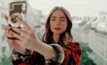 Lily Collins in "Emily in Paris" taking a selfie