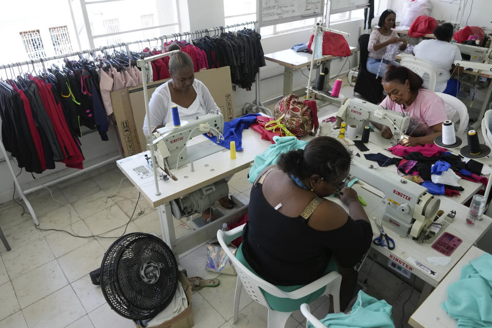 Lupe, top left, sews at a cooperative created to support women who've been victims of Colombia's long-running conflict in Buenaventura, Colombia, Wednesday, Aug. 16, 2023. Lupe, who spoke on condition of using only her first name, for fear of retribution, said gangs threatened to kill her son and kidnap her granddaughter, pushing them to flee to the United States by night, carrying only small backpacks. (AP Photo/Fernando Vergara)