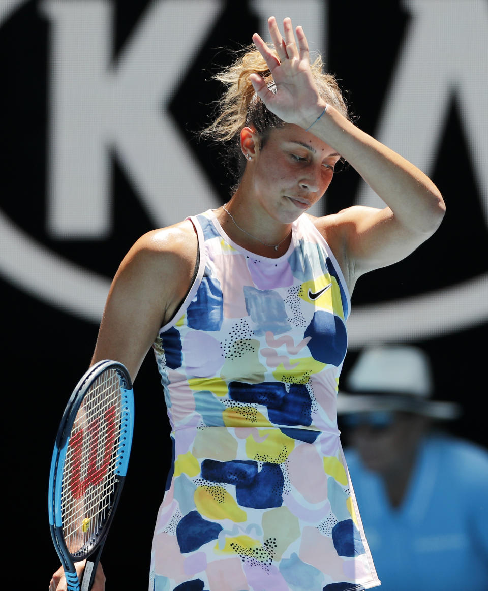 In this Jan. 21, 2020, photo, Madison Keyes of the U.S. reacts after her shot hit the net during her first round singles match against Russia's Daria Kasatkina at the Australian Open tennis championship in Melbourne, Australia. It might just be the most insincere gesture in sports: A tennis player signals an apology after a ball clips the net tape and trickles over, producing a winner, an obviously accidental winner, to end a point. (AP Photo/Andy Wong)
