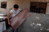 Mohamed Abdul Rahman, 18, checks sheets if papyrus is dry at a workshop in al-Qaramous village
