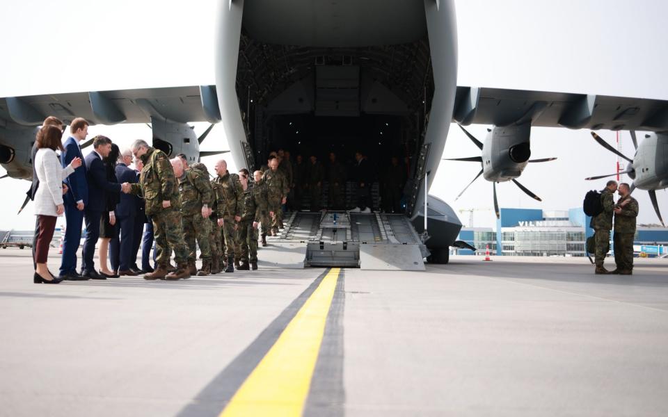 机场停机坪上的一排士兵从一架大型军用飞机中走出来后向立陶宛平民致意