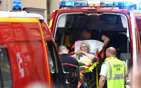 Emergency workers stretcher a woman to a waiting ambulance after a suspected package bomb blast along a pedestrian street in the heart of Lyon, southeast France - Credit: &nbsp;PHILIPPE DESMAZES/AFP