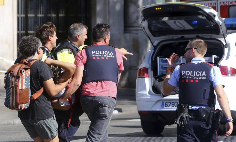 Officers help one of the victims of the Barcelona attack (Rex)