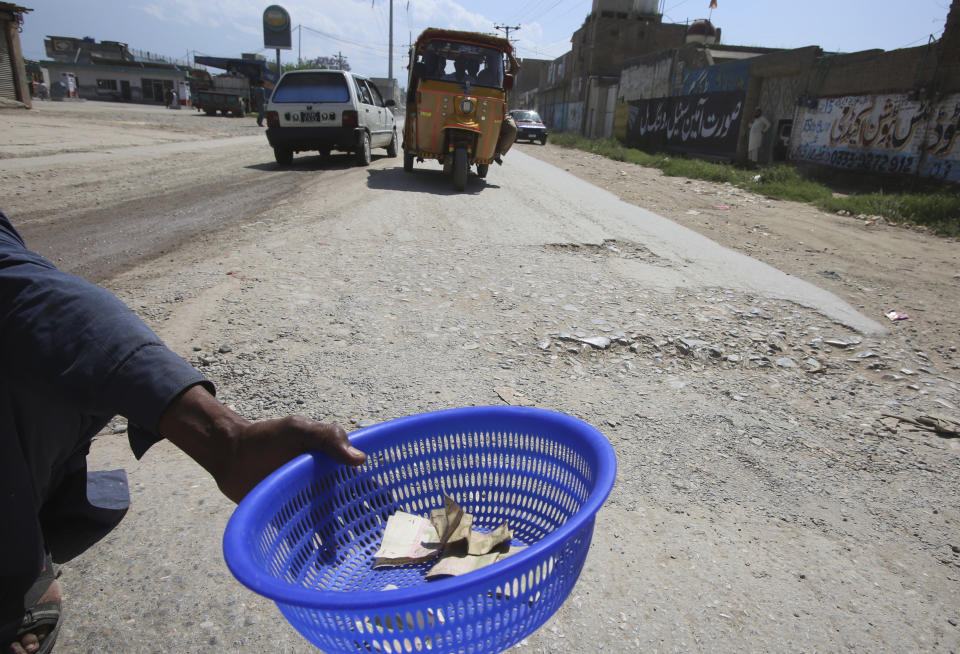 In this May 6, 2020 photo, a man begs at a roadside during a lockdown to help to contain a spread of coronavirus in Peshawar, Pakistan. For millions of people who live in poor and troubled regions of the world, the novel coronavirus is only the latest epidemic. They already face a plethora of fatal and crippling infectious diseases: polio, Ebola, cholera, dengue, tuberculosis and malaria, to name a few. The diseases are made worse by chronic poverty that leads to malnutrition and violence that disrupts vaccination campaigns. ( AP Photo/Muhammad Sajjad)