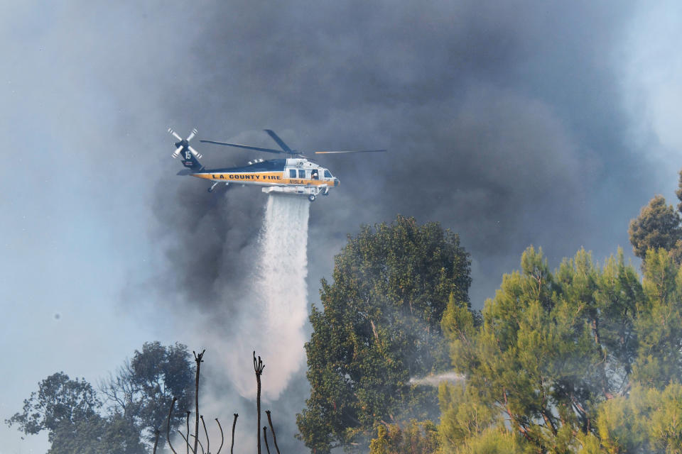 <p>A helicopter drops water over a house on a hilltop in Bel Air, California, on December 6.</p>