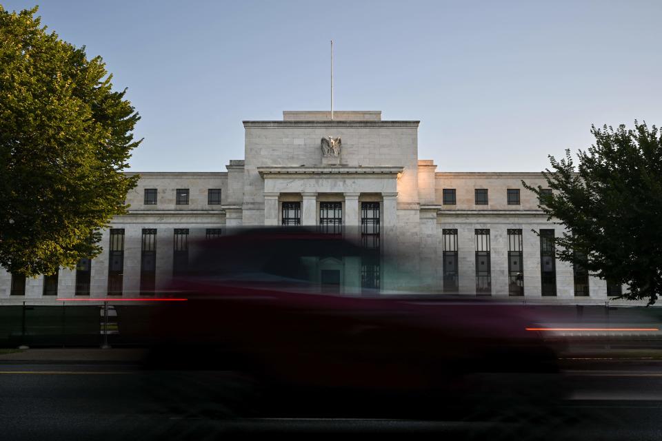 Morning traffic along Constitution Avenue passes the US Federal Reserve in Washington, DC on August 18, 2022. - US central bankers remain committed to raising interest rates further to quell rising prices, but agreed it would be appropriate to slow the pace of the hikes 
