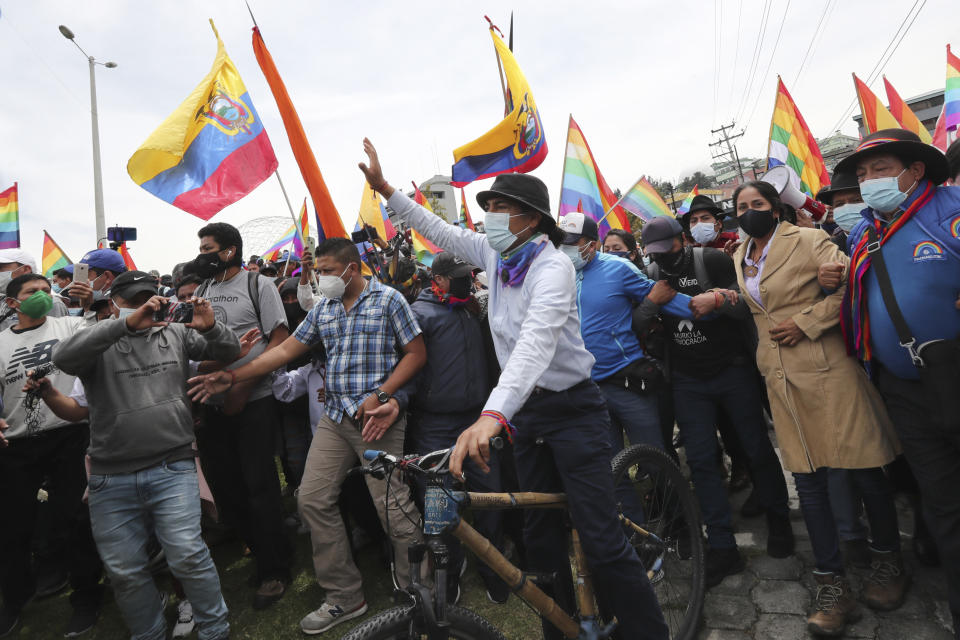 El candidato presidencial Yaku Pérez saluda desde una bicicleta mientras él y sus partidarios llegan a Quito, Ecuador, después de una marcha de protesta de una semana desde el sur hasta la capital, el martes 23 de febrero de 2021. Pérez está pidiendo al Consejo Nacional Electoral una recuento de las boletas electorales presidenciales del 7 de febrero, diciendo que él es el subcampeón legítimo, no Guillermo Lasso, quien las autoridades electorales anunciaron que quedó en segundo lugar y se enfrentará al principal candidato Andrés Arauz en una segunda vuelta en abril. (AP Foto/Dolores Ochoa)