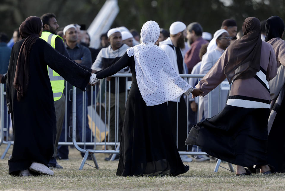 Mourners hold hands following a burial ceremony at the Memorial Park Cemetery in Christchurch, New Zealand, Friday, March 22, 2019. Funerals continued following the Friday, March 15 mosque attacks where 50 worshippers were killed by a white supremacist. (AP Photo/Mark Baker)