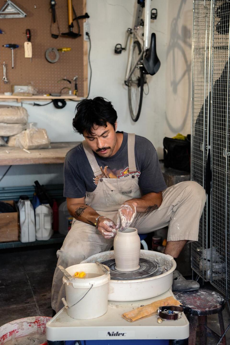 Daniel Dooreck works on a piece on a pottery wheel inside his ceramics studio.