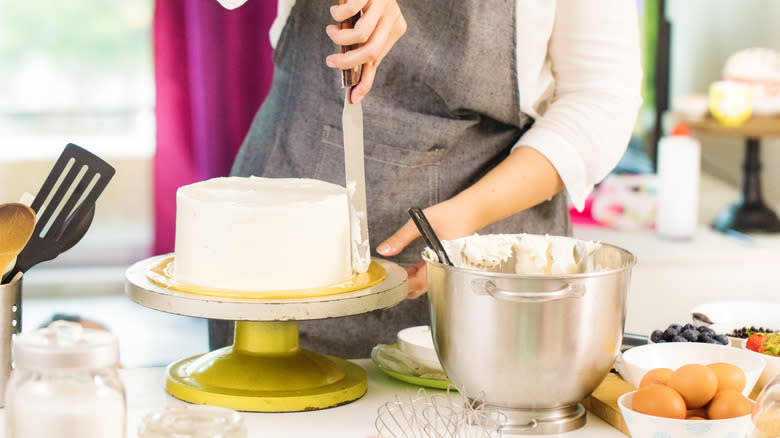 Person spreading frosting on a cake