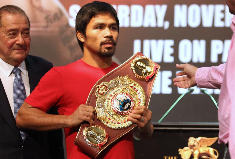 Philippine boxing icon Manny Pacquiao holds the title belt after posing for photographs during a pre-fight press conference in Macau on November 20, 2013