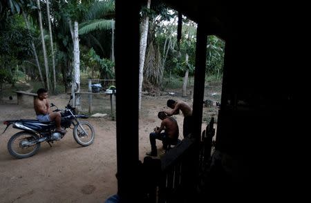 A youth cuts a friend's hair outside his house, in Chico Mendes Extraction Reserve in Xapuri, Acre state, Brazil, June 23, 2016. REUTERS/Ricardo Moraes