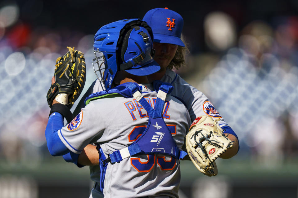 Sam Clay, relevista de los Mets de Nueva York, abraza al puertorriqueño Michael Pérez, su compañero de batería, tras el primer encuentro de una doble cartelera ante los Filis de Filadelfia, el sábado 20 de agosto de 2022 (AP Photo/Chris Szagola)