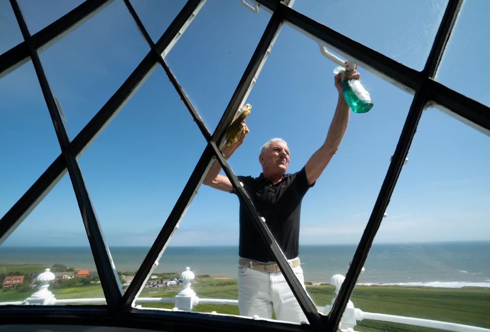 <p>Chairman of Friends of Happisburgh Lighthouse David Vyse cleans the windows on the lantern room of Happisburgh Lighthouse in Norfolk as it prepares to reopen to visitors after being closed since 2019 due to the Coronavirus pandemic. Picture date: Thursday July 15, 2021.</p>
