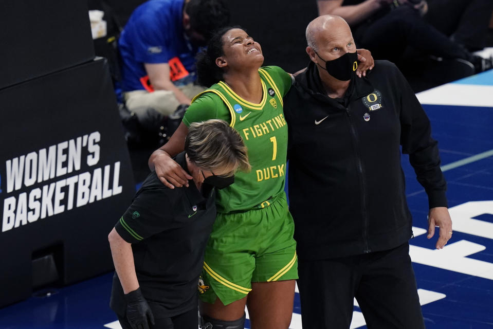 Oregon forward Nyara Sabally (1) is helped off of the court by head coach Kelly Graves, right, after she was injured during the second half of a college basketball game against the Louisville in the Sweet Sixteen round of the women's NCAA tournament at the Alamodome in San Antonio, Sunday, March 28, 2021. (AP Photo/Eric Gay)