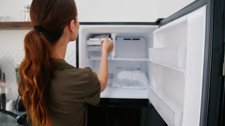 woman reaching into freezer