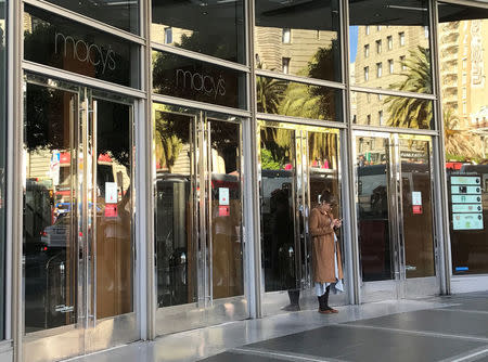 An employee stands outside the closed doors of Macy's department store, during a power cut in San Francisco, California, U.S. April 21, 2017. REUTERS/Alexandria Sage