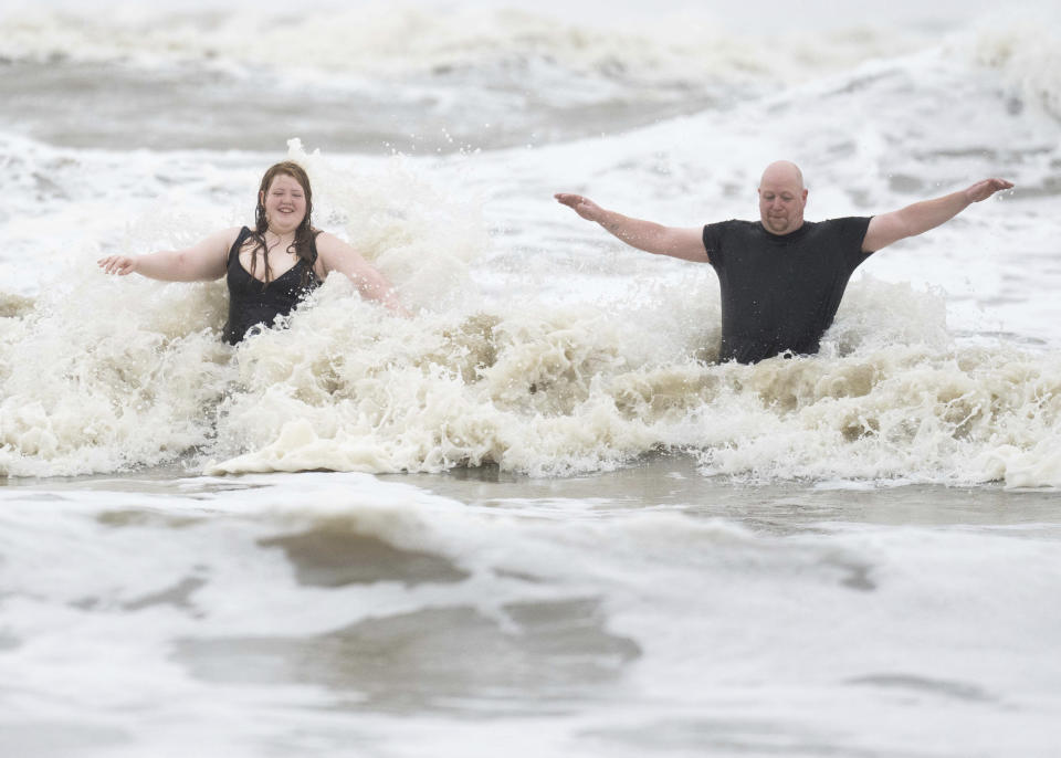 Jeremy Reddout and his daughter, Elexus, enjoy the waves between Murdoch's and Pleasure Pier as rain falls, Wednesday, June 19, 2024, in Galveston, Texas. Tropical Storm Alberto has formed in the southwestern Gulf of Mexico, the first named storm of what is forecast to be a busy hurricane season. (Jason Fochtman/Houston Chronicle via AP)