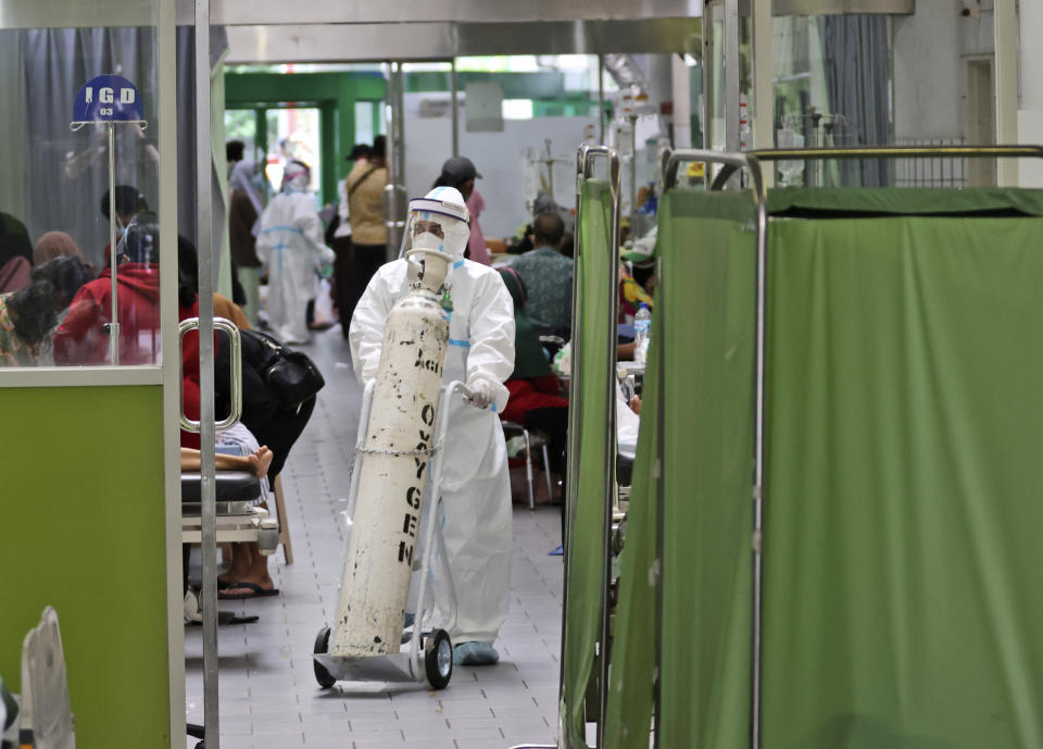 A paramedic pushes an oxygen tank at the emergency ward of an overcrowded hospital amid COVID-19 cases, in Surabaya, East Java, Indonesia, Friday, July 9, 2021. The world's fourth most populous country is running out of oxygen as it endures a devastating wave of coronavirus cases and the government is seeking emergency supplies from other countries, including Singapore and China. (AP Photo/Trisnadi)