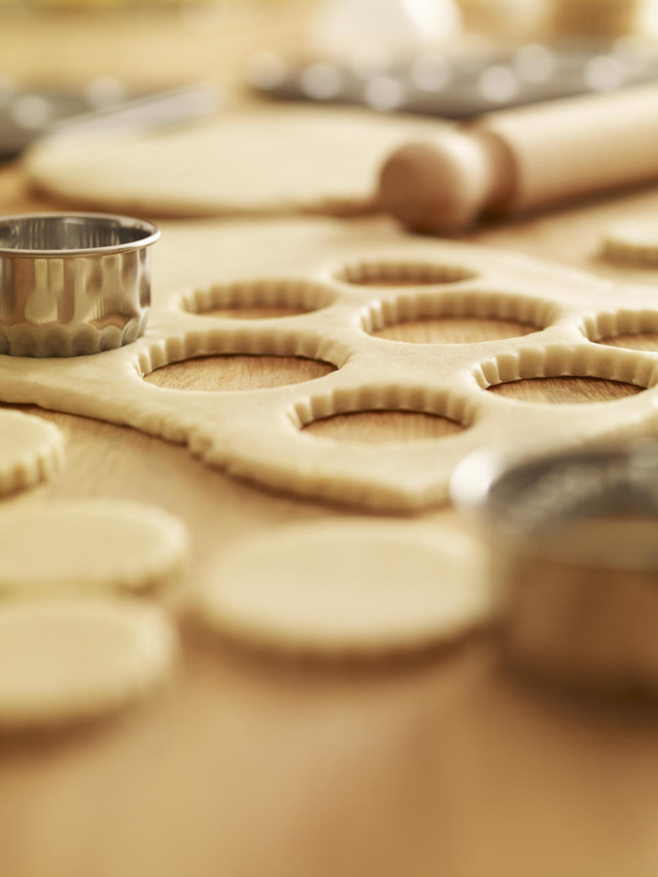 Circular cookie cutters and dough on a wooden surface, ready for baking sheets