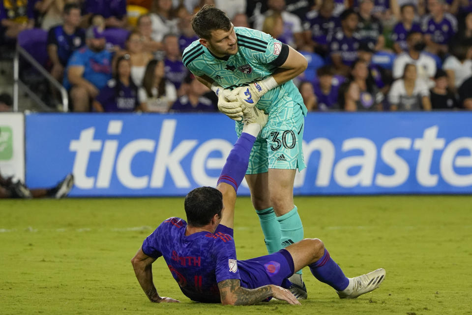 FC Dallas goalkeeper Maarten Paes (30) helps Orlando City defender Kyle Smith with a leg cramp during the second half of an MLS soccer match, Saturday, May 28, 2022, in Orlando, Fla. (AP Photo/John Raoux)