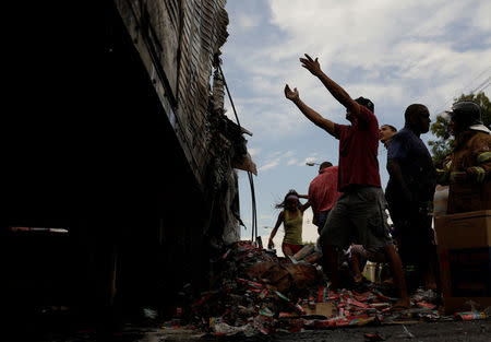 Residents loot a truck burned during violent clashes between rival gangs at a street near Brasil avenue near Cidade Alta slum in Rio de Janeiro, Brazil, May 2, 2017. REUTERS/Ricardo Moraes