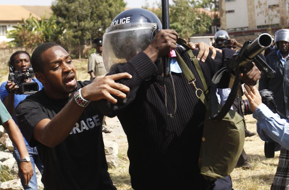 Kenyan activist Mwangi attempts to help a riot policeman injured in a scuffle during a protest by students of Langata primary school against a perimeter wall erected by a private developer around their school playground in Nairobi