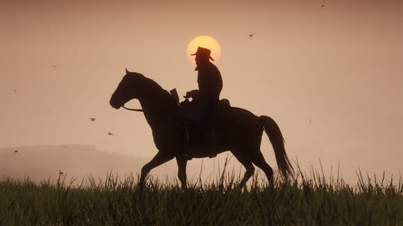 Screenshot of Red Dead Redemption 2 depicting a cowboy riding a horse in the open country against setting sun in the background.