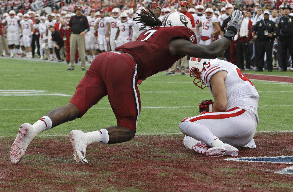 Wisconsin tight end Sam Arneson (49) catches a pass for a touchdown in front of South Carolina defensive end Jadeveon Clowney, left, during the first half of the Capital One Bowl NCAA college football game in Orlando, Fla., Wednesday, Jan. 1, 2014.(AP Photo/John Raoux)