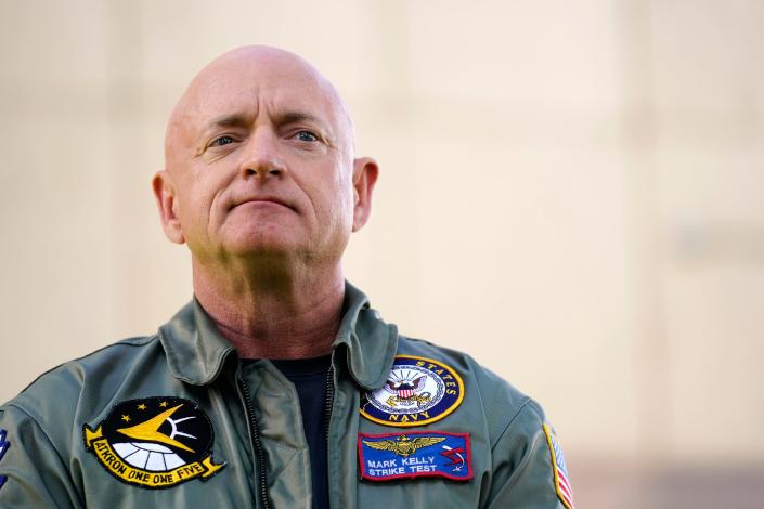 Mark Kelly wears a US Navy bomber jacket with a skeptical look