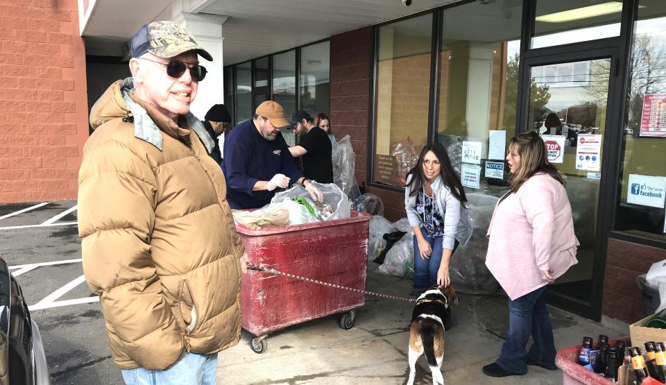 Dighton resident Bill Bradshaw, left, visits Town Line Redemption Center on Wednesday, Feb. 8, 2023, with his dog Mickey, who receives a biscuit from Assistant Program Manager Jeannine Camara-Jackson while Program Supervisor Kim Garrison looks on.