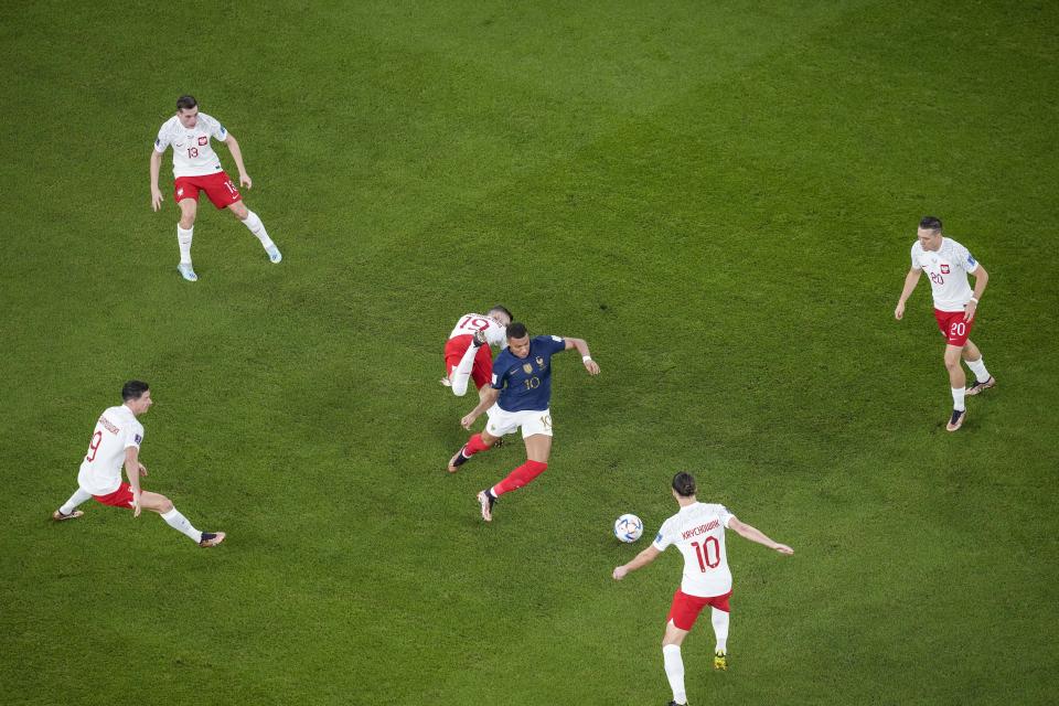 El delantero francés Kylian Mbappé (centro), rodeado de jugadores de Polonia durante el partido por los octavos de final del Mundial, el domingo 4 de diciembre de 2022, en Doha, Qatar. (AP Foto/Thanassis Stavrakis)